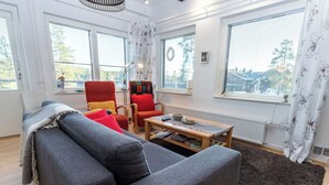 Ein modernes Wohnzimmer mit einem grauen Sofa, einem roten Sessel und einem Holztisch.