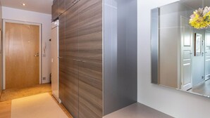 Ein moderner Flur mit einem Holzschrank, einem Spiegel und einer Lampe.