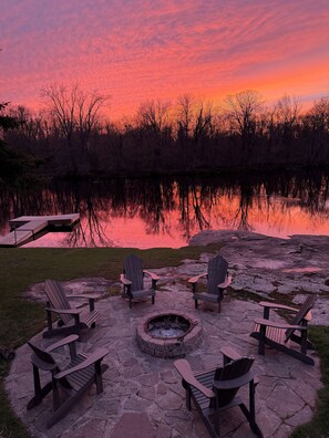 A lakeside patio with Adirondack chairs and a fire pit. - Beautiful waterfront cottage w/ hot tub, firepit, fireplace and so much more! (tweed)