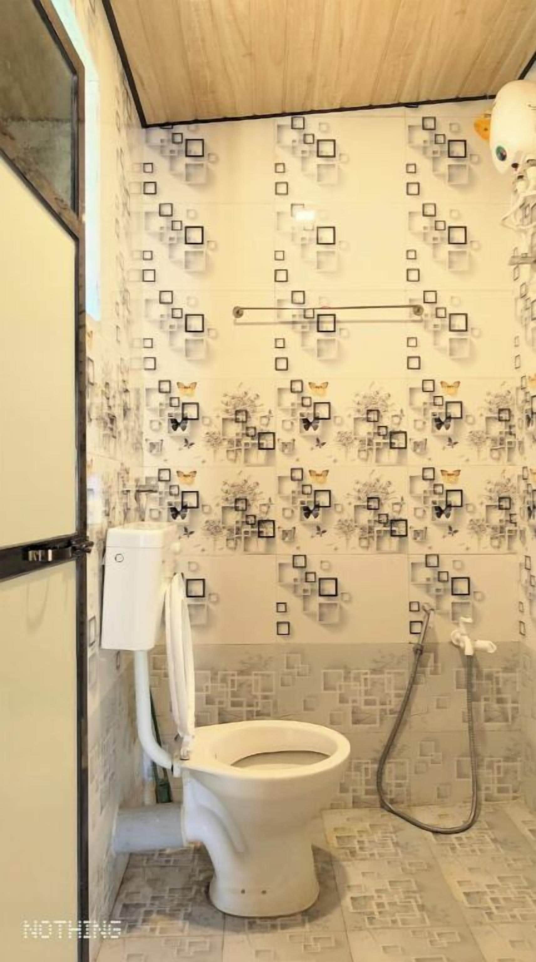 Een badkamer met toilet, douche en betegelde muren met vierkante patronen.
