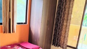 A room with a bed, a wardrobe, and a window with curtains. - Mauli cottage (Murud)