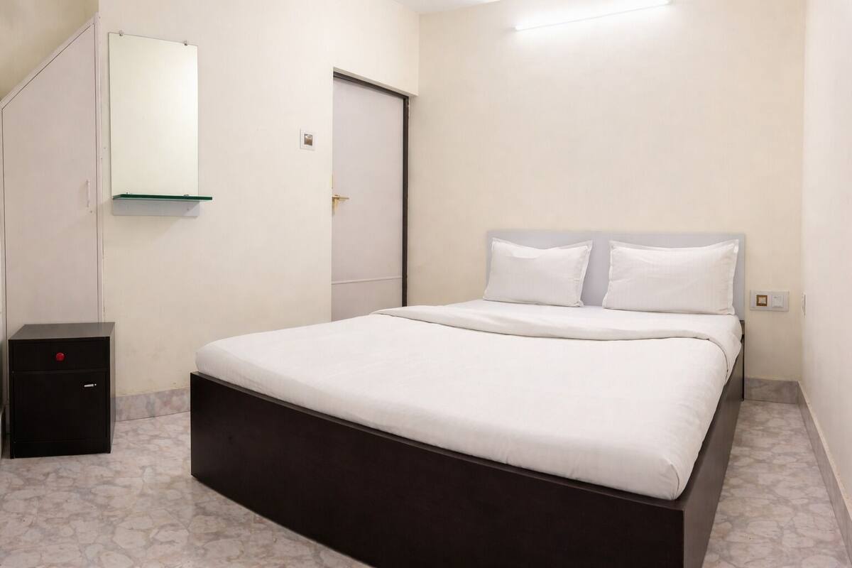 A bedroom with a bed, a nightstand, a wardrobe, and a mirror.