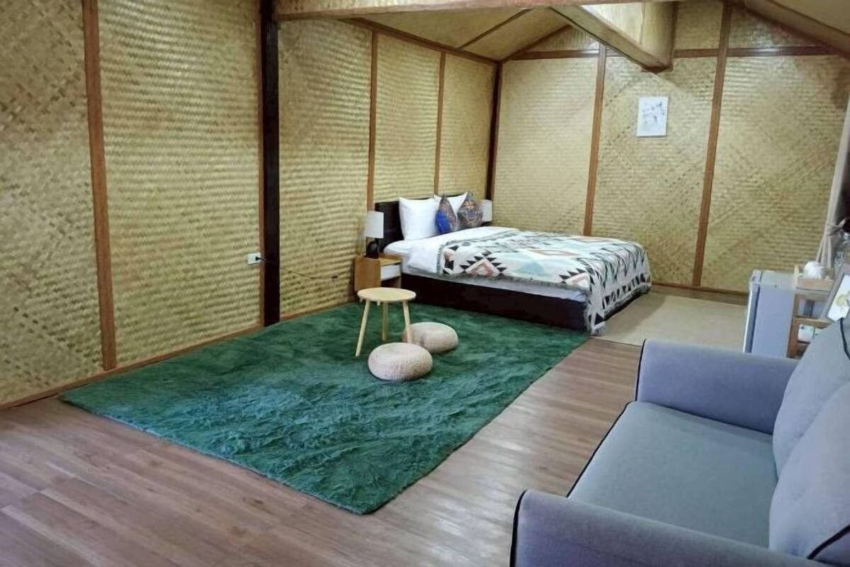Ein Zimmer mit einem Bett, einem grünen Teppich, einem Hocker und einer Couch.