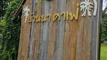 A wooden sign with Thai script, likely indicating a location or establishment.