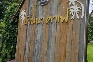 Un cartello di legno con caratteri thailandesi, probabilmente indicante un luogo o una struttura.