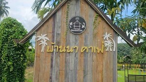 Eine Holzhütte mit einem Schild, auf dem "Banna Cafe" und thailändische Schriftzeichen stehen.