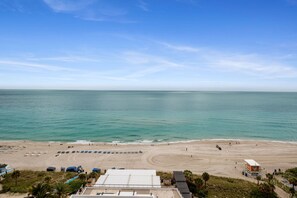 Ein Strand mit einem Rettungsturm, Sonnenschirmen und freiem Blick auf das Meer.