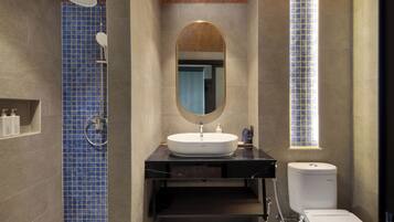 Un baño moderno con un espejo ovalado grande, un lavamanos blanco y una ducha con azulejos azules.