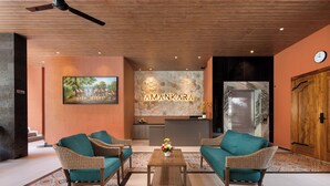 A lobby with wicker furniture, a reception desk, a clock, and a stone wall with the name 'AMANKARA'. - Amankara Canggu (Tibubeneng)