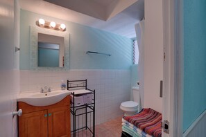 Ein Badezimmer mit Waschbecken, Spiegel, Waschtisch, Toilette und Duschbereich.