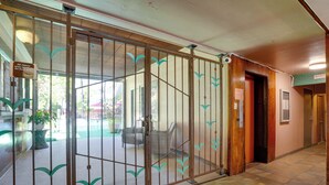 Un espace d’accueil doté d’une porte vitrée, d’un panneau indiquant les règles à respecter pour les visiteurs et d’une plante en pot.