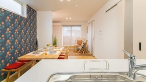 Eine moderne Küche mit weißer Arbeitsplatte, Spüle aus Edelstahl und einem Holzespeisetisch mit roten Kissen.
