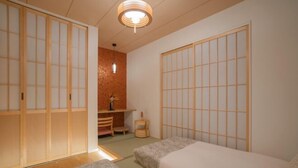 Ein traditioneller japanischer Raum mit Tatami-Boden, Shoji-Bildschirmen und einem niedrigen Holztisch mit Stuhl.