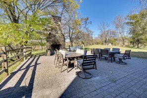 Eine Terrasse im Freien mit Kamin aus Stein, Holzmöbeln und einem Pflasterboden.