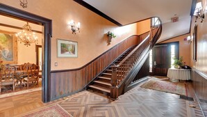 A grand staircase with a wooden finish and a curved design, leading to an upper floor. - Walk to Golf Course: Spacious Rough River Retreat! (Falls of Rough)