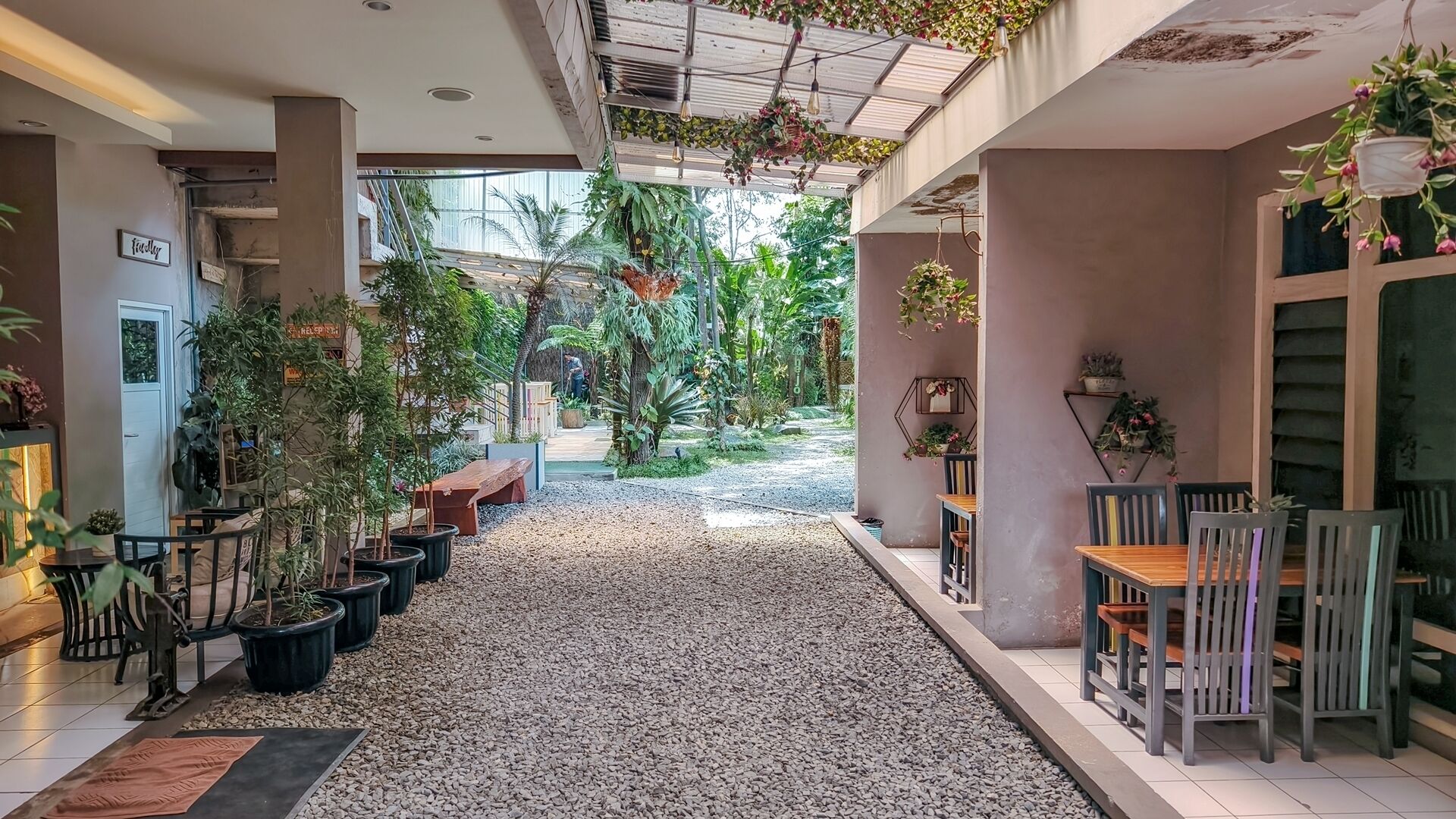A covered outdoor area with seating, potted plants, and a gravel path.