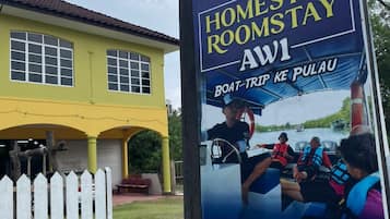 Un cartel de Homestay AW1 anuncia un viaje en barco a Pulau.