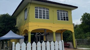 A two-story yellow building with large windows and a white picket fence in front. - OYO 91250 Roomstay Awie (Setiu)