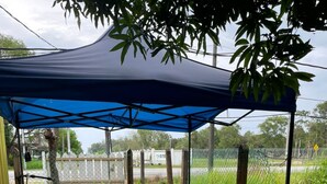 A covered outdoor seating area with round tables and stools. - OYO 91250 Roomstay Awie (Setiu)