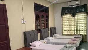 A hotel room with three single beds, a wooden nightstand, a small cabinet, and a window with curtains. - OYO 91250 Roomstay Awie (Setiu)