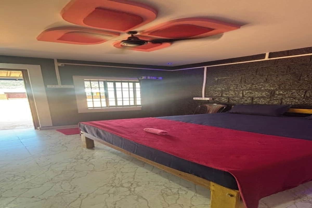 Une chambre à coucher comprenant un lit, un ventilateur de plafond, une fenêtre et une porte donnant sur un espace extérieur.