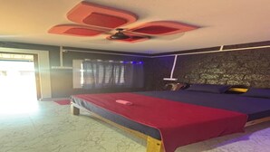 Ein Schlafzimmer mit einem Bett, einem Deckenventilator, einem Fenster mit Vorhängen und einer Wand mit strukturierter Oberfläche.