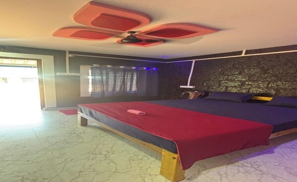 Quarto com cama, ventoinha no teto, janela com cortinas e parede com textura.