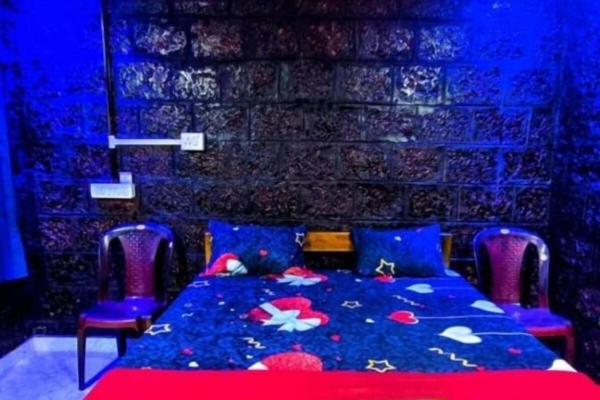 Une chambre à coucher comprenant un lit, deux chaises, une table de chevet et un mur orné d’un motif texturé.