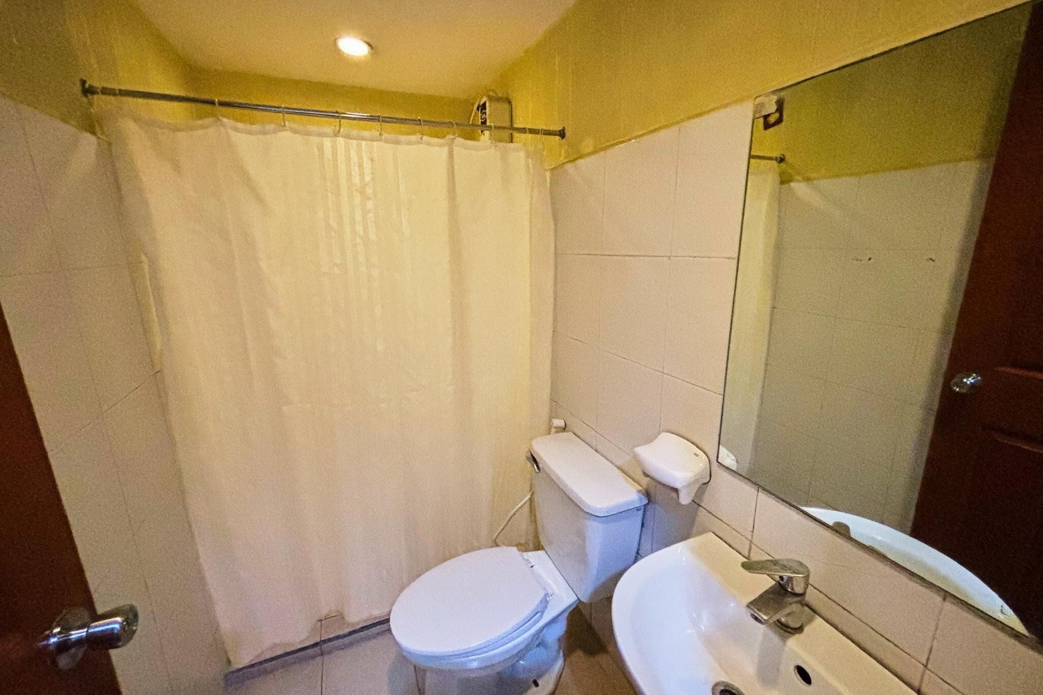 A small bathroom with a toilet, sink, and a shower curtain.
