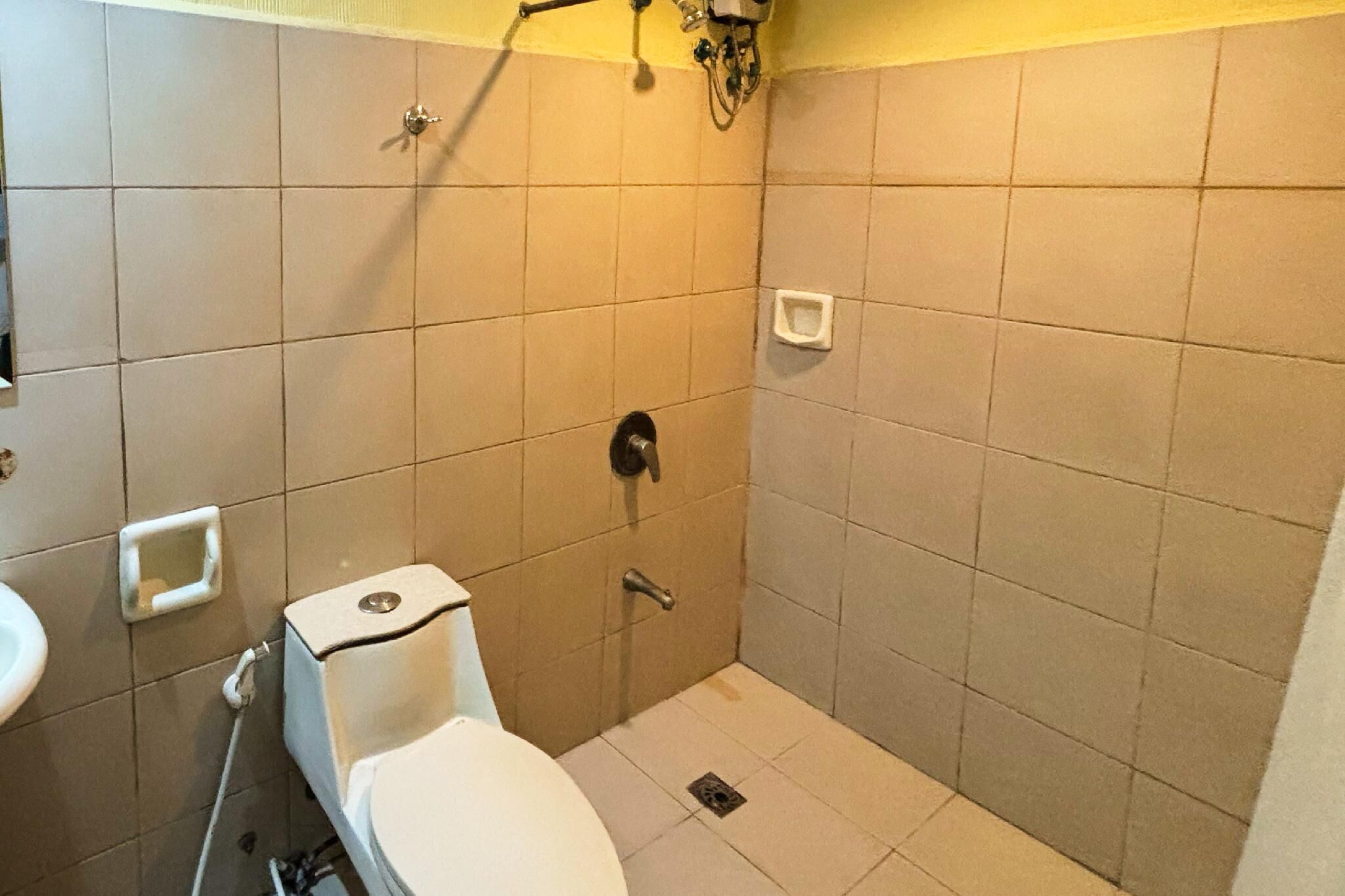 Un baño pequeño con azulejos, un inodoro, lavamanos y ducha.