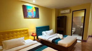 A hotel room with two beds, a painting on the wall, an air conditioning unit, and a bathroom visible through an open door. - Comfy Inn Mabini Manila (Manila)