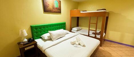 A hotel room with a single bed, a bunk bed, a nightstand with a lamp, and a painting on the wall.