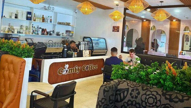 A coffee shop interior with a counter, seating area, and decorative lighting. - Comfy Inn Mabini Manila (Manila)