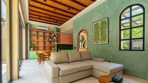 A modern living room with a sectional sofa, a wooden coffee table, and a dining area with a green kitchen in the background. - La Jolla Canggu (Canggu)