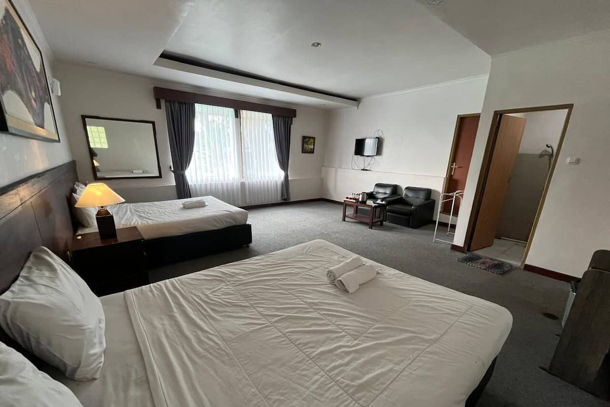 A hotel room with two beds, a desk, a chair, a TV, and a window with curtains.