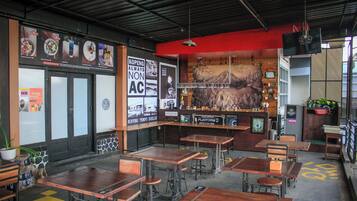 A café with wooden tables and chairs, a counter with a menu, and a mural on the wall.