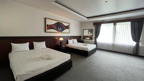 Een hotelkamer met twee bedden, een groot schilderij, een raam met gordijnen en een plafondlamp.
