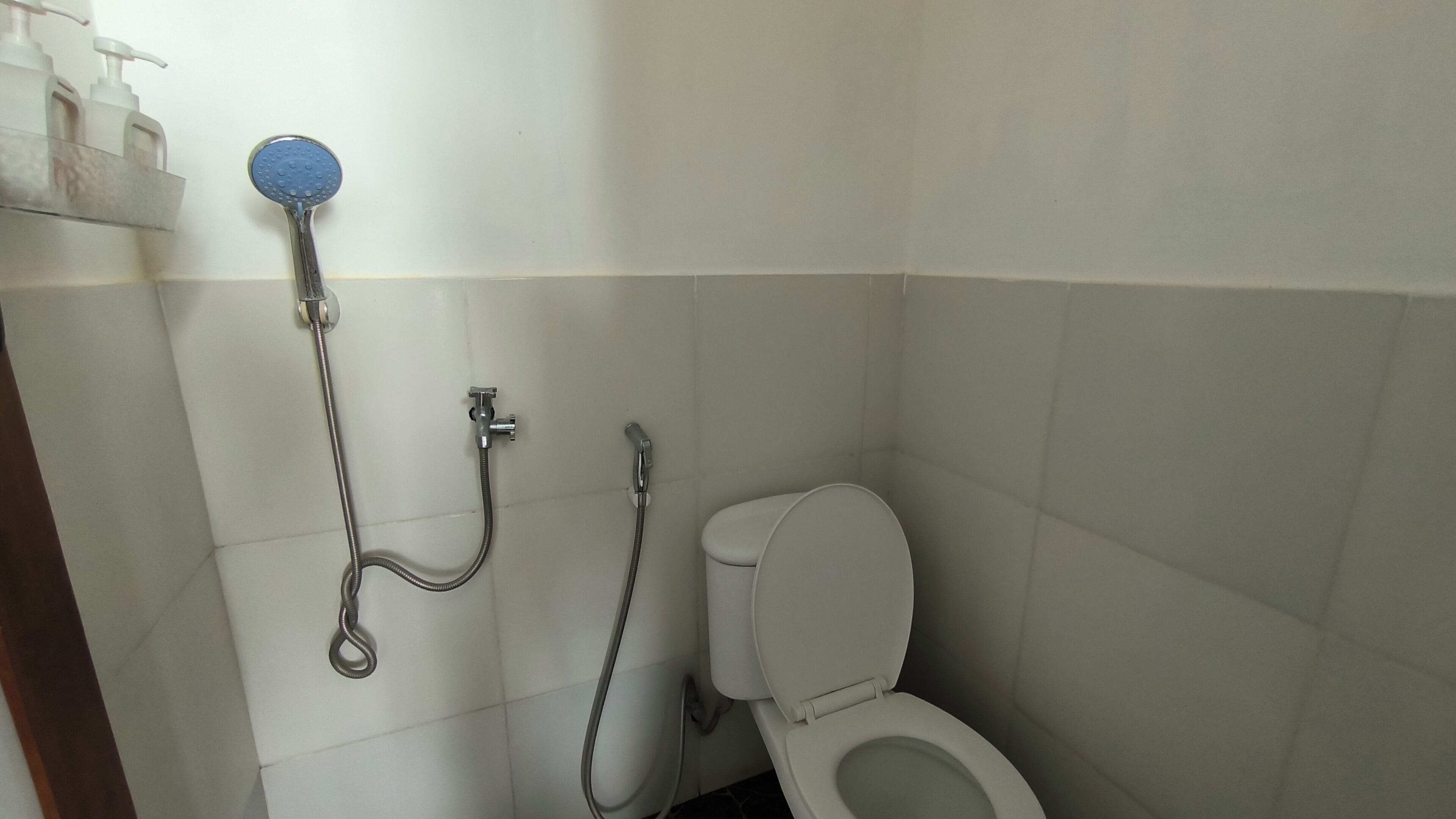 A bathroom with a toilet, a shower, and a hand dryer.