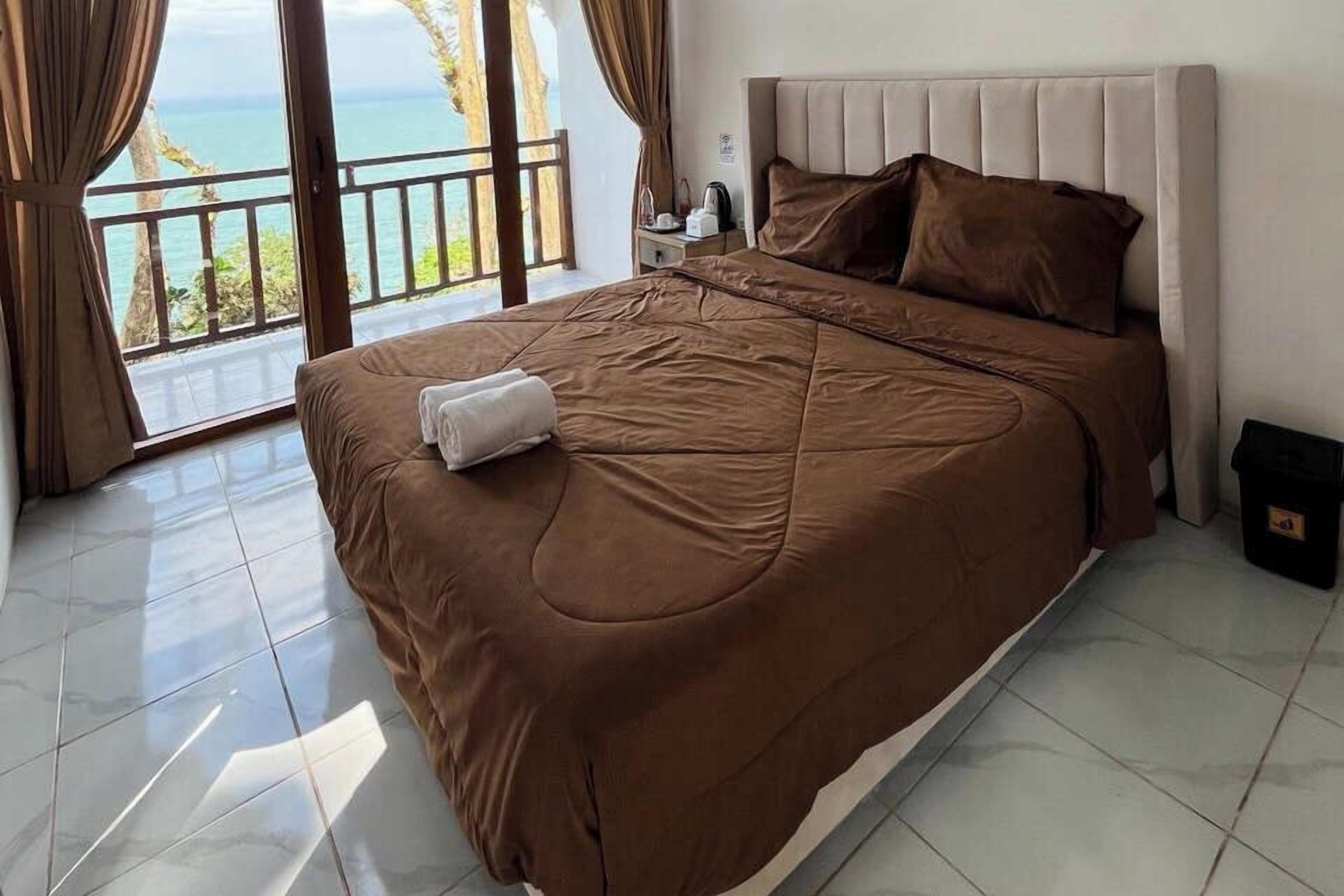 Un dormitorio con una cama grande, una mesita de noche y vistas al mar.