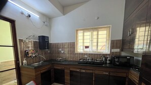Cocina pequeña con estufa a gas, microondas y armarios de madera.