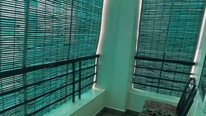Una habitación con piso de madera, una silla con diseño de hojas y una ventana con persianas horizontales.