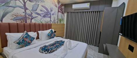 A hotel room with a bed, a desk, a ceiling fan, and an air conditioning unit.