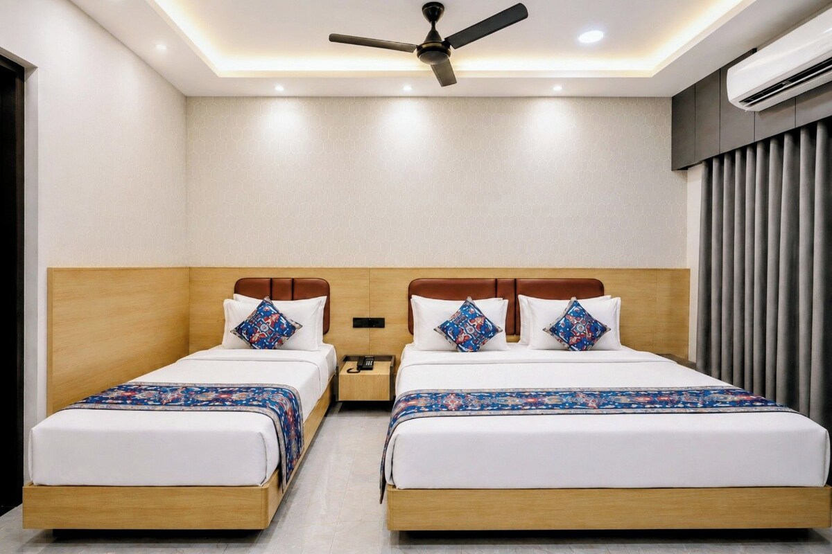 A hotel room with two beds, a ceiling fan, and an air conditioning unit.