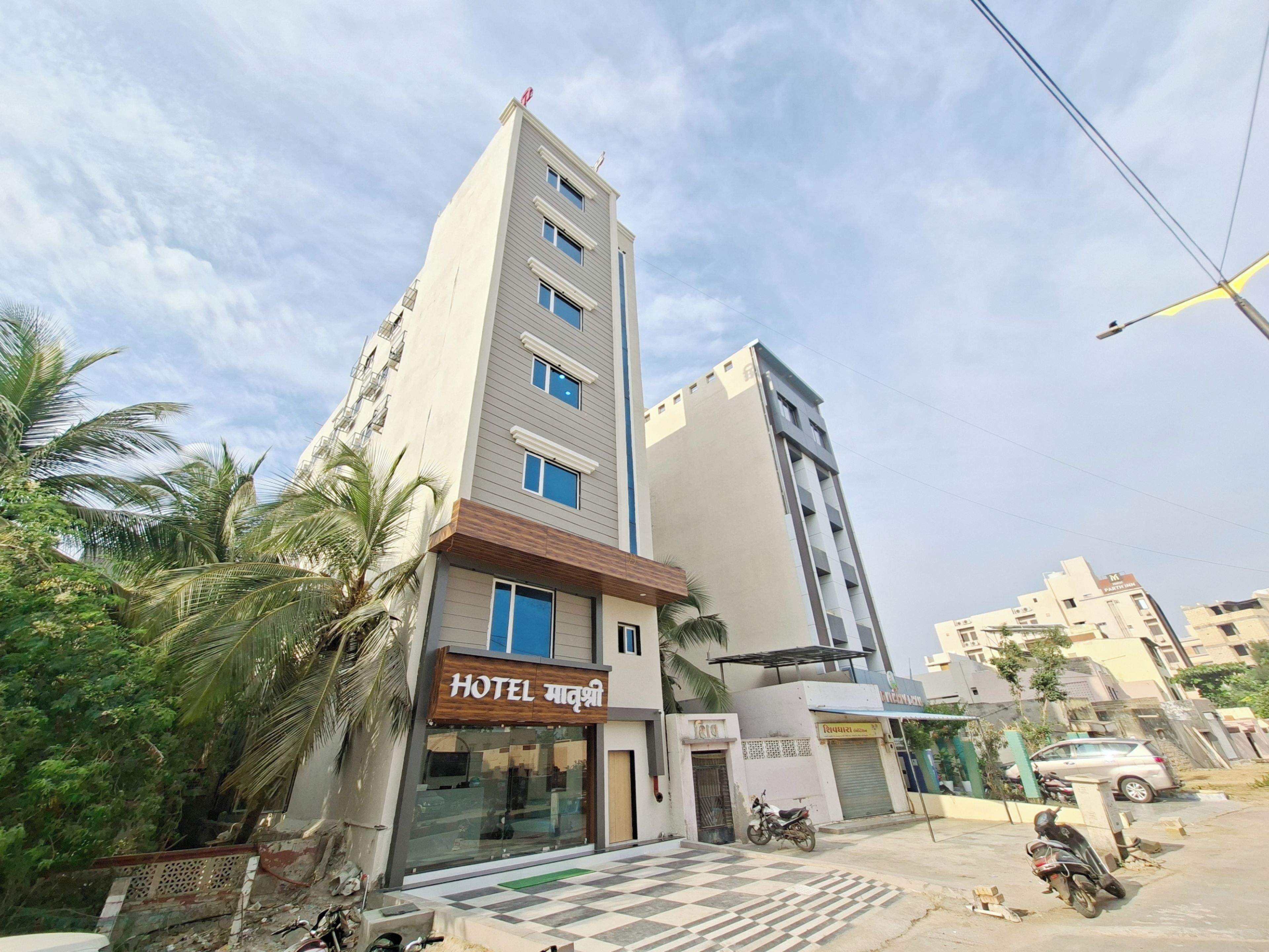 A hotel with a modern facade, a checkered entrance, and a parked motorcycle.