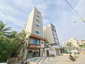A hotel with a modern facade, a checkered entrance, and a parked motorcycle. - Matrushree Hotels - Near Shree Dwarkadhish Temple (Dwarka)