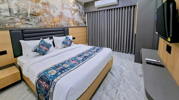 A modern hotel room with a large bed, a flat-screen TV, and a ceiling fan. - Matrushree Hotels - Near Shree Dwarkadhish Temple (Dwarka)