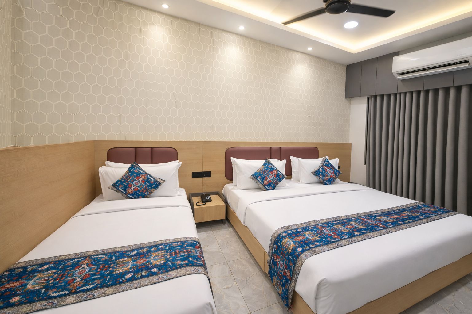 A hotel room with two beds, a nightstand, an air conditioning unit, and a ceiling fan.