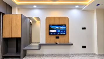 A modern reception area with a mounted TV displaying various streaming services, a wooden cabinet, and a marble floor.