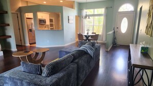 Una sala de estar con un sofá modular, una mesa de comedor y una cocina al fondo.