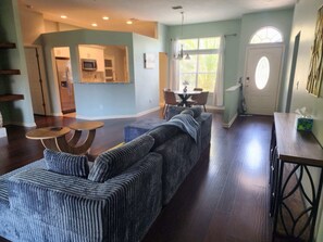 Una sala de estar con un sofá modular, una mesa de comedor y una cocina al fondo.